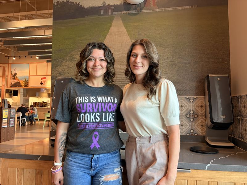 Caitlin standing with an advocate wearing a Domestic Violence Awareness shirt